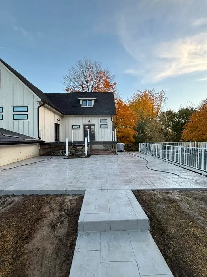 Colored broom-finished patio slab beside a brick home