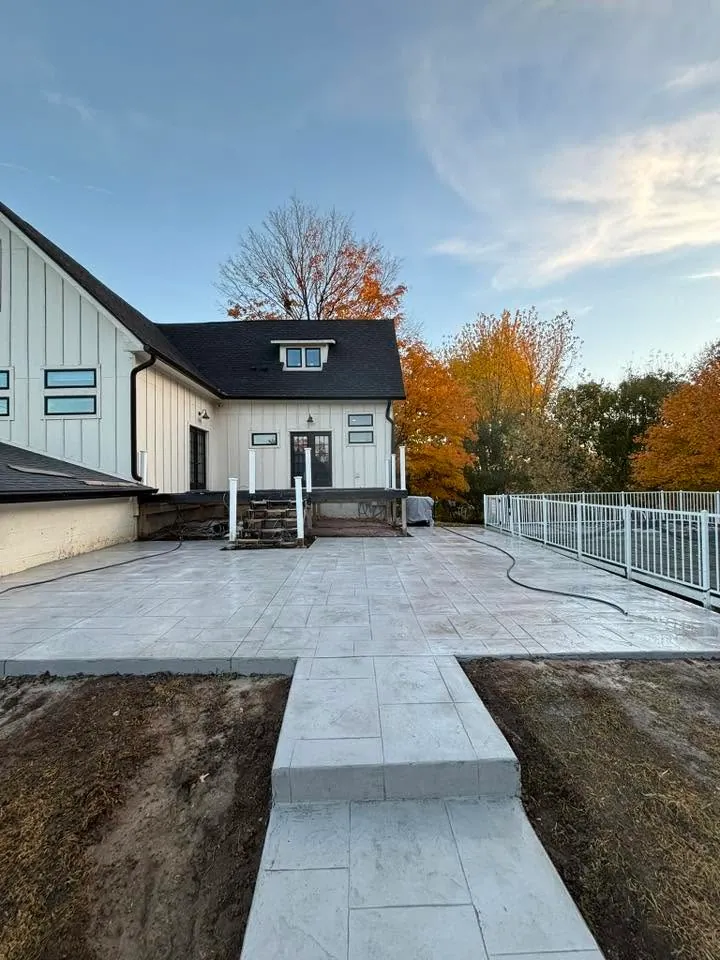 Colored broom-finished patio slab beside a brick home